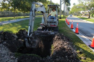 A man on the back of a tractor digging a hole.
