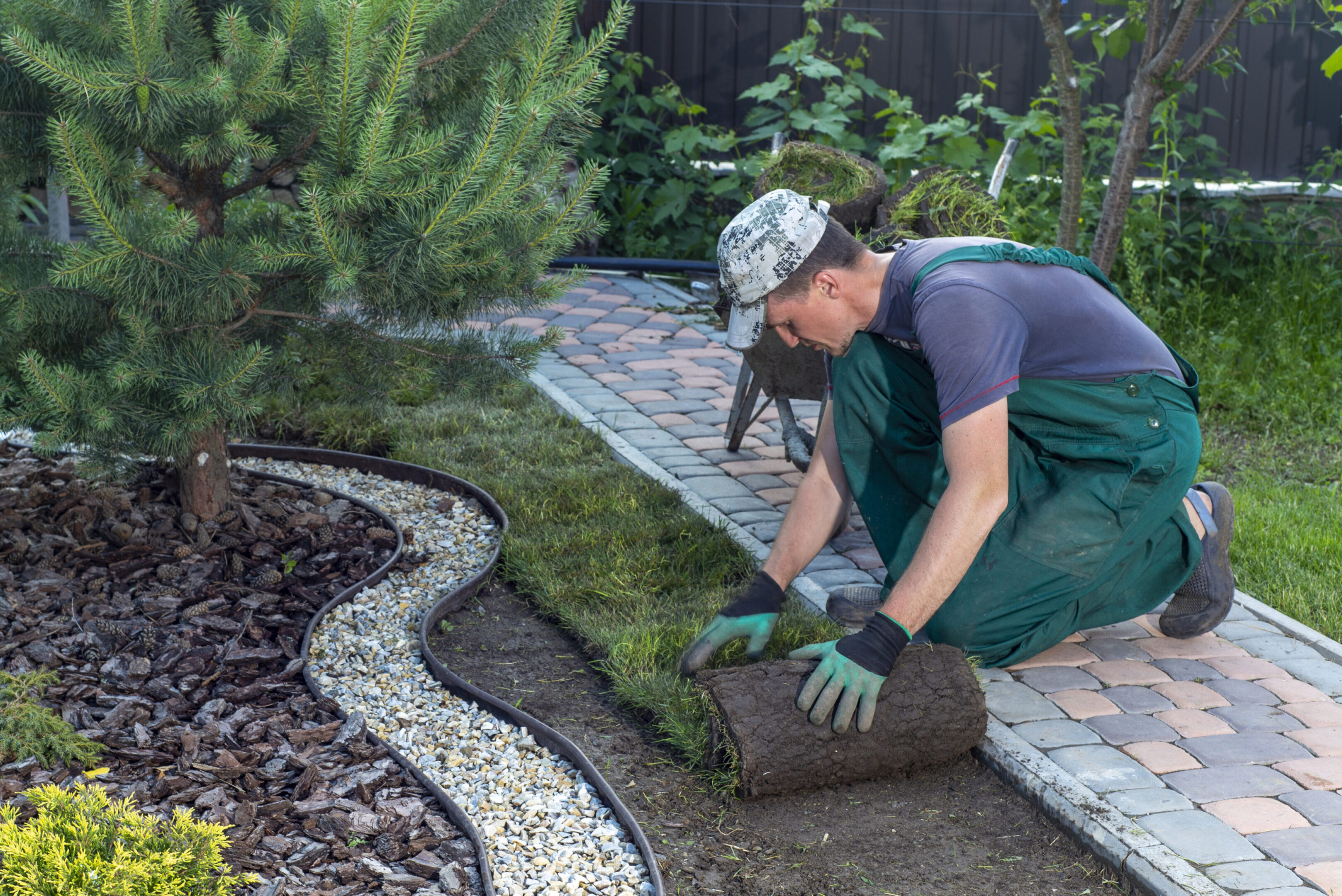 A gardener laying bricks to create a garden path.